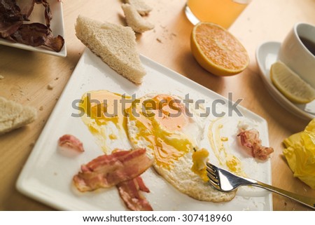 Concept of a standard everyday breakfast. Concept of a busy lifestyle. Bacon and fried eggs, fresh orange juice and tea with lemon. Selective focus on the egg yolk.