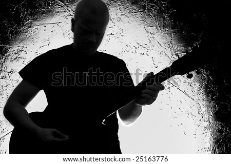 Guitar player on stage. Silhouette. Lighted background.Strong contrast. Black&white.