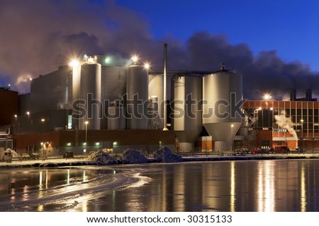 Paper mill by winter night immediately after sunset, when sky has turned blue.