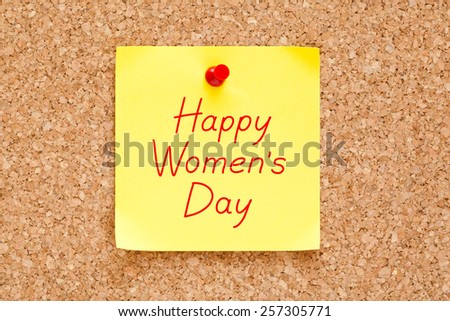 Happy Women\'s Day written on a sticky note pinned on a cork bulletin board.