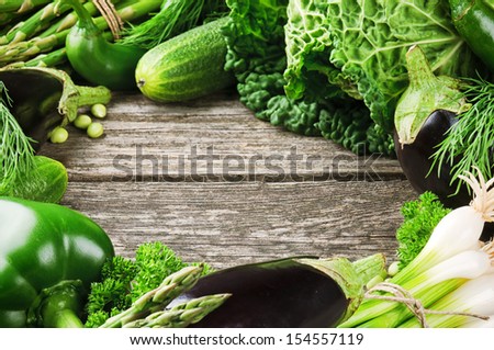 Frame with fresh organic vegetables on wooden background