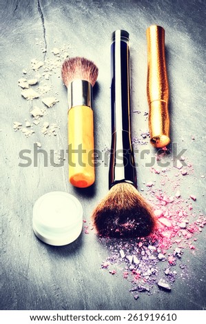 Makeup brushes and makeup products on dark background