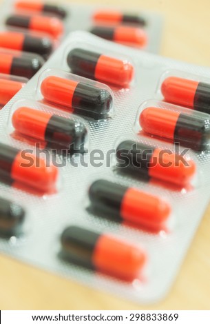 Medicine red and black in capsule on wood table, Selective focus