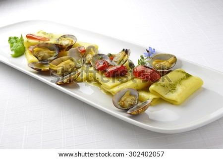 Pasta Dish Paccheri Macaroni with Clams Grilled Tomatoes and Basil Sauce in long white plate