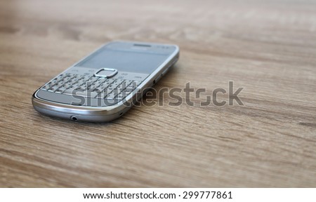 Silver mobile phone on the wooden table