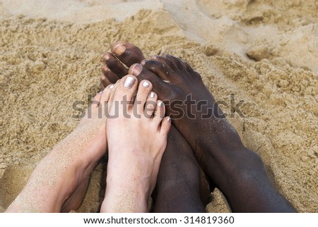 Two pair of multicultural touching feet at beach  playful love