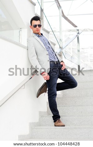Portrait of a young handsome man, model of fashion, wearing tinted sunglasses