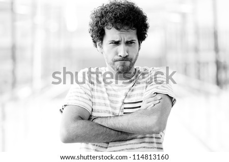 Portrait of good looking guy with angry face in urban background