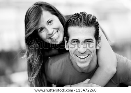 Portrait of smiling young man piggybacking his pretty girlfriend in the park