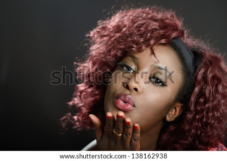 Portrait of beautiful black woman on black background blowing a kiss. Afro hairstyle. Studio shot