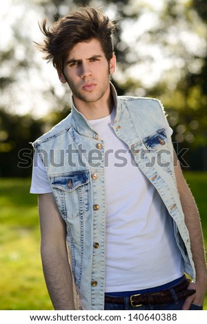 Portrait of a young handsome man, model of fashion, with modern hairstyle in urban background