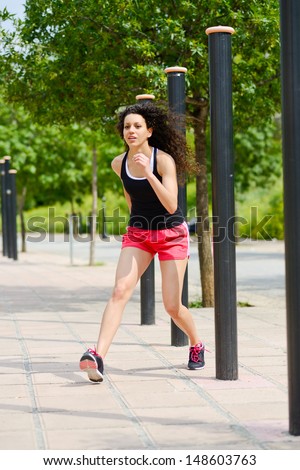 Portrait of young cheerful smiling woman in sports wear in urban background
