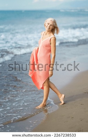 Foto Bild Ältere Frau am Ufer eines Strandes. Ältere Frau, die ihren Ruhestand an einem Strandort genießt.