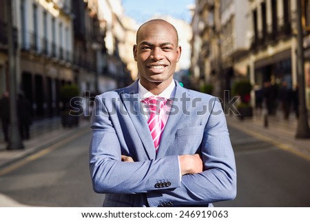 Portrait of handsome black man smiling, wearing suit in urban background