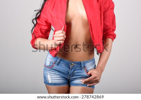 Hispanic woman, model of fashion wearing red jacket and denim shorts on white background. Studio shot