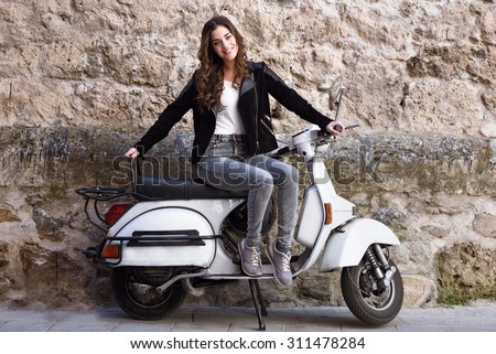 Young woman in urban background woman climb on a scooter motorcycle wearing casual clothes