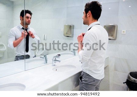 Man getting dressed in a public restroom with mirror