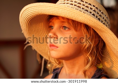 The little girl in a straw hat looks afar