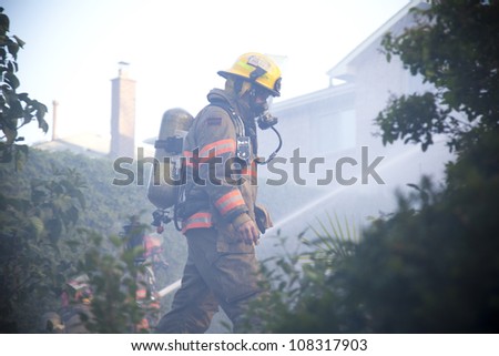 BRAMPTON, ONTARIO -  JULY 20 2012 - Firefighter walks through the backyard as fellow firefighters try to douse a house fire burning at 20 Esker Drive in Brampton Ontario on July 20, 2012