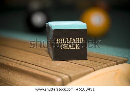 Close up shot of billiard chalk on pool table with balls in background