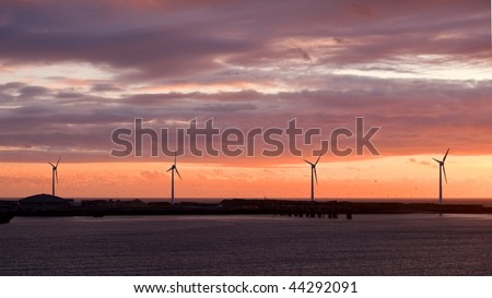 Wind turbine off the sea under sunset