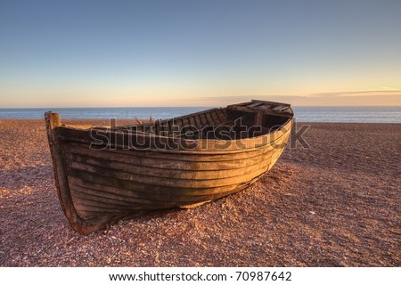 An old boat on Brighton beach by sunset