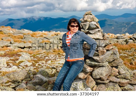 Beautiful woman sitting on a Stone marker atop Mount Washington