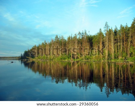 This is the picture of the quiet Karelian lake and the distant forest under the light of the rising sun
