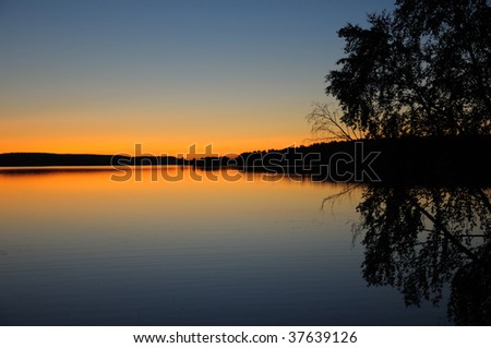 The final stage of a sunset above the huge lake in Karelia region. The picture is colorful and relaxing.