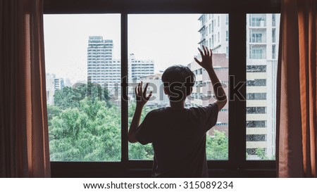 Someone standing by window with raindrops on a rainy day,Lonely silhouette in a window