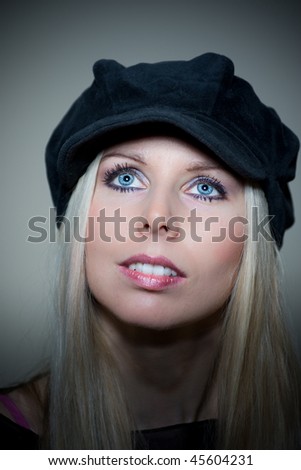 Women with blond hair, blue eyes and red lips. Black hat on head. Studio shoot.