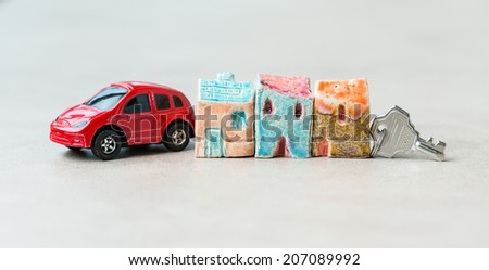 Three toy ceramic houses with keys  and toy red car on the left side