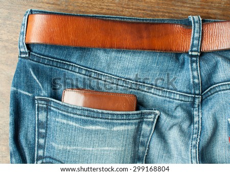 Brown wallet in back blue jeans and brown leather belt