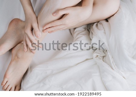 Image, Stock Photo Flatlay of woman rubbing cream in her legs in bed