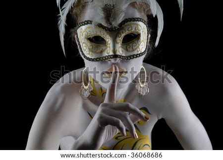 Portrait of beautiful young girl in gold flowers bodyart in venice mask holding finger at her lips