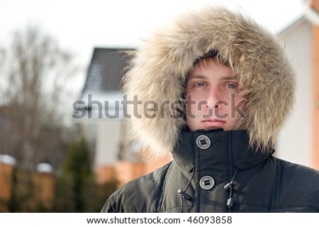 Winter time - man in warm jacket with furry hood in the yard