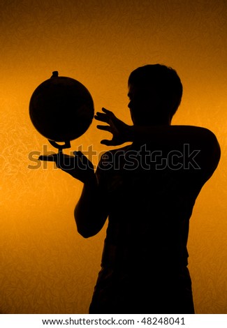 Discover the world - silhouette of man holding globe in the darkness