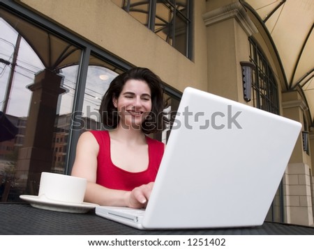 A woman in a casual read shirt browses the internet while having her morning coffee.