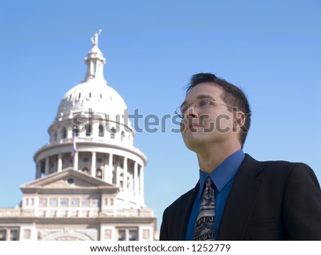 A man in a suit looking out over the Texas State Capitol.