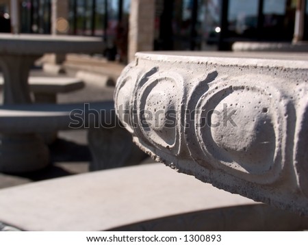 A concrete picnic table outside a strip mall.  Shallow DOF, flocus is on the side of the table.