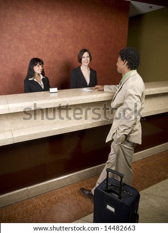 A hotel employee cheerfully welcomes guests.
