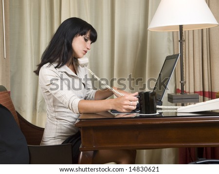 A businesswoman works late into the night on a laptop in her hotel room while on a business trip.