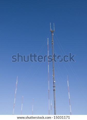 Towering radio and television broadcast antenna against a crisp blue sky.