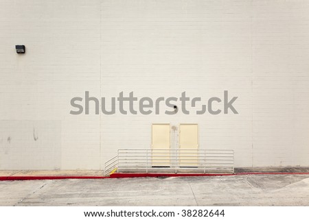 A blank wall and exit door on a large building.