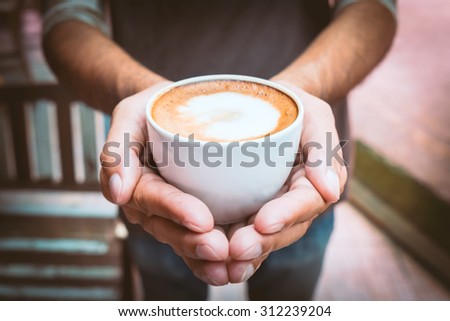 A picture of a young man holding a cup of coffee in coffee shop  - Vintage style