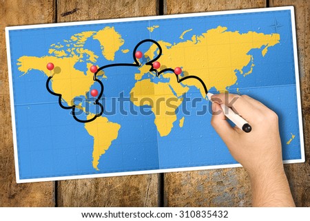 Hand tracking travel itinerary with black felt tip or marker on world map