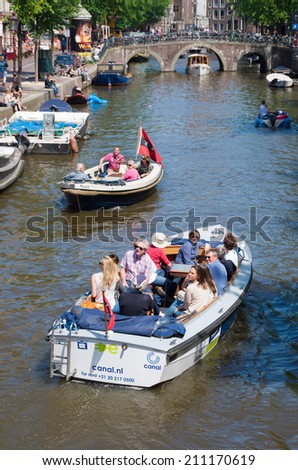 AMSTERDAM - MAY 18, 2014: UNKNOWN tourists in boats on an amsterdam canal. Amsterdam counts 165 canals with a total length of 100 km.