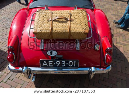 OLDENZAAL, NETHERLANDS - APRIL 27, 2015: Red oldtimer car with suitcase during the 14th orange tour. This annual tour takes places during the king\'s birthday celebrations, a national holiday.
