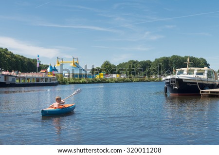 OMMEN, NETHERLANDS - AUGUST 9, 2015: Unknown boy playing with his canoe in the Regge river. The Regge area is a popular holiday region in the eastern netherlands