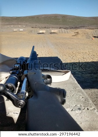 30-06 on a rifle range. This is rifle is colored black loaded with the bolt out. The rifle is pointing down range